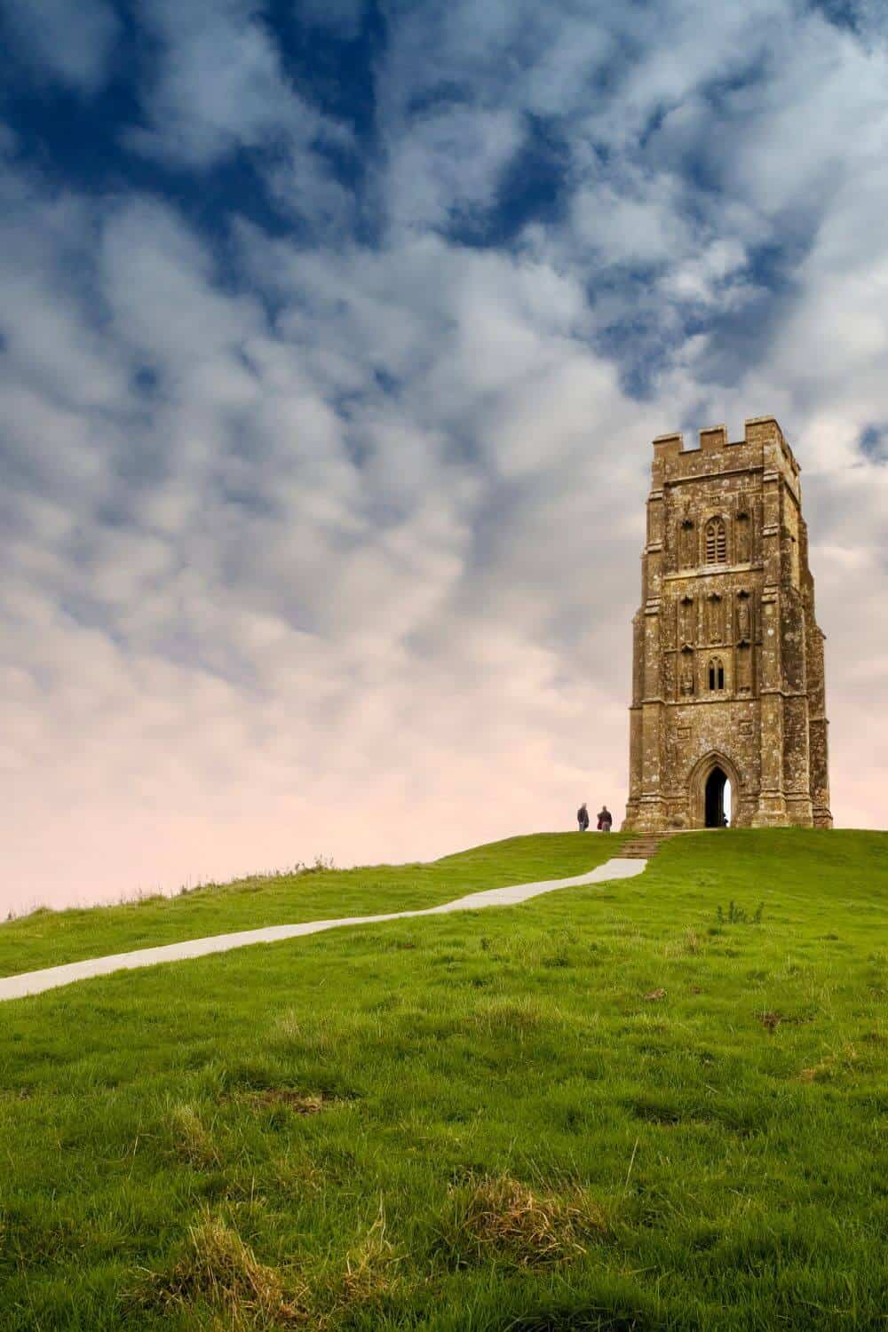 Glastonbury Tor - The ruined St. Micheals church can be seen along with the path leading up it below a cloudy sky