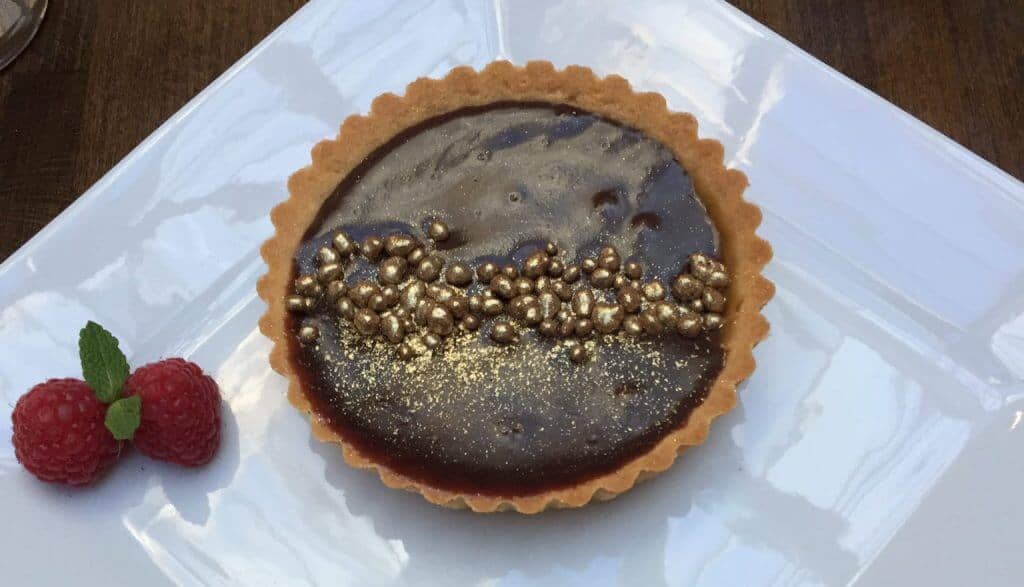 A plate with a chocolate tart topped with gold balls