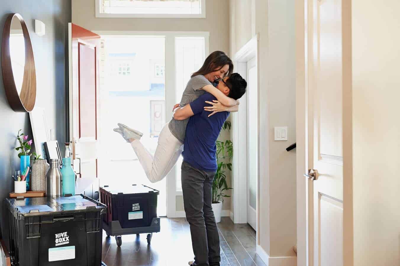 A men and a woman moving in to their new home, and hugging each other